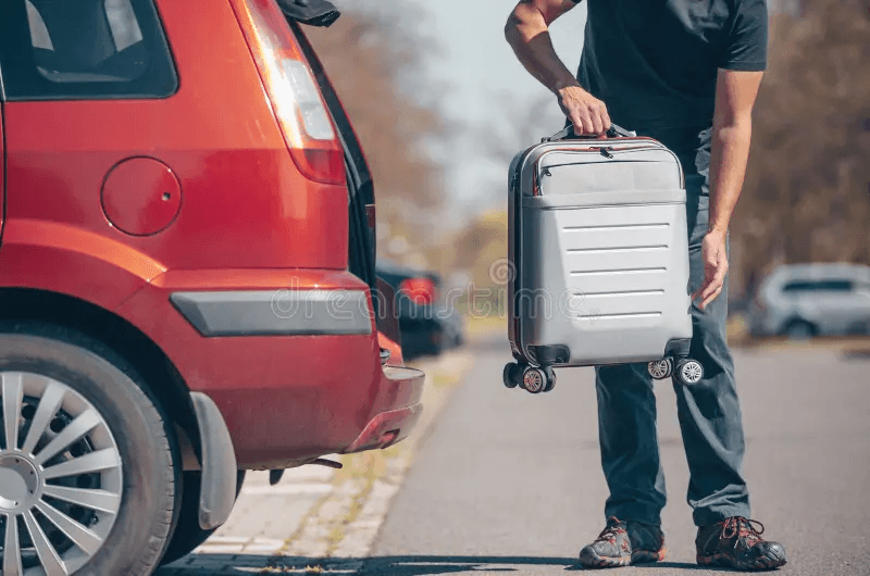 Traveler loading luggage into a rental car